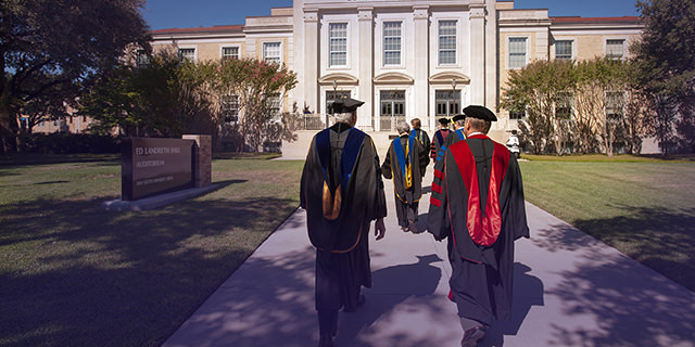 TCU faculty walk to Ed Landreth Hall wearing regalia
