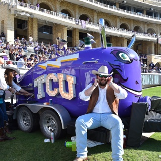 A large purple train horn mounted on a trailer with the "TCU" logo lit up in bright white lights