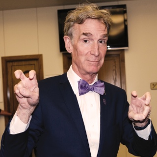 Visiting author and television host Bill Nye holds up both hands in the two-fingered Go Frogs hand gesture.