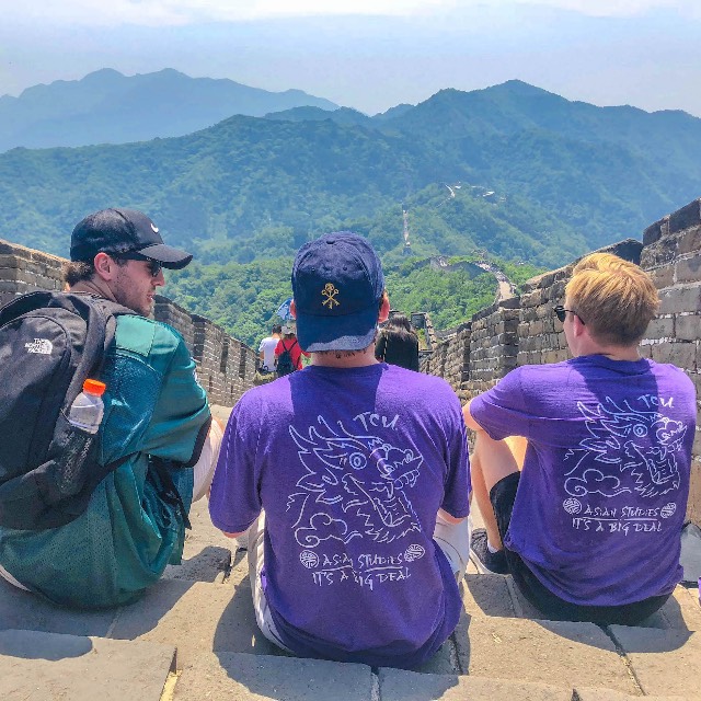 Three students sit atop the Great Wall of China