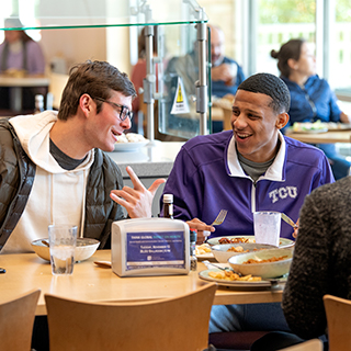 Two male TCU students share a laugh over lunch at the campus main dining hall
