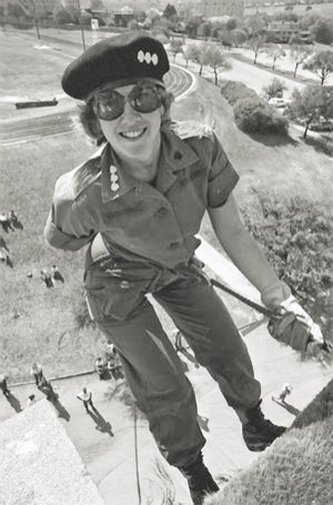 Female ROTC cadet rappelling down a hillside